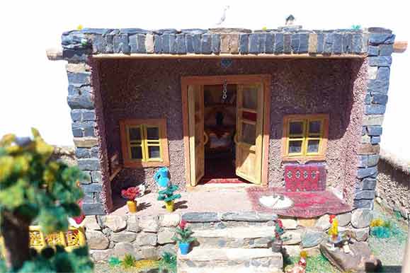 نمای روبروی ماکت مینیاتوری یک خانه سنتی ایرانی با درب باز، پله‌های سنگی و پنجره‌های چوبی.